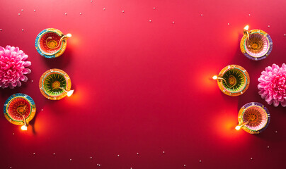 Happy Diwali - Clay Diya lamps lit during Diwali, Hindu festival of lights celebration. Colorful traditional oil lamp diya on red background