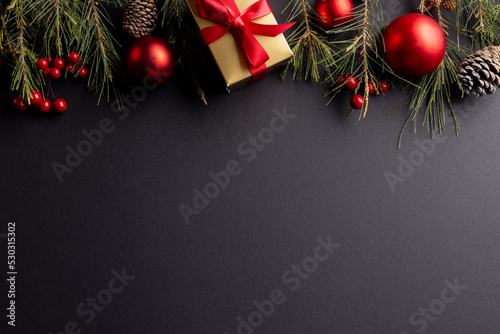 Image of christmas decorations with baubles and copy space on black background