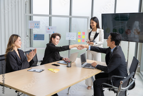 Cheerful young Asian businessman Excited and glad applauded. About successful startup projects Happy Asian colleagues celebrating business success in office meeting.