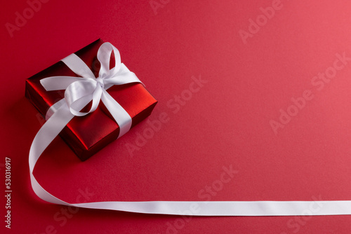 Image of christmas decoration with red gift and copy space on red background © vectorfusionart