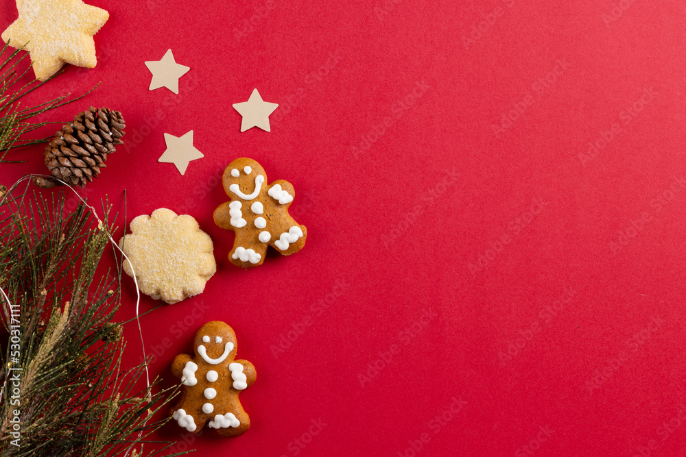 Image of gingerbread man biscuits and christmas decoration with copy space on red