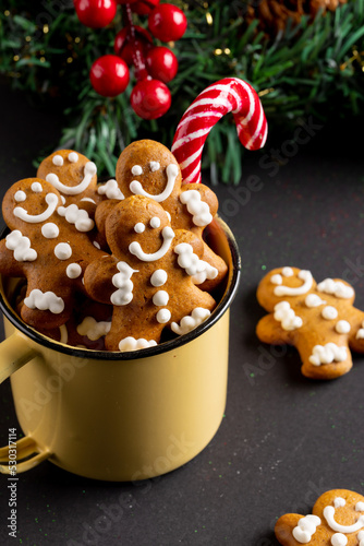 Image of yellow mug with christmas gingerbread men and candy cane on black background