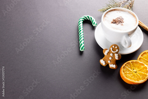 Image of cup of cappuccino coffee and christmas gingerbread man with copy space on grey