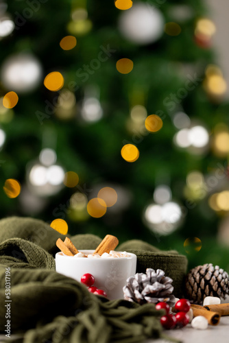 Image of cup with hot chocolate and marshmallows and copy space over christmas tree