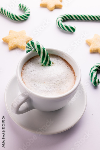 Green christmas canes, christmas cookies and cup of coffee over white background