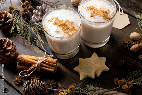 Image of two glasses of christmas milk with cinnamon sticks and christmas decorations