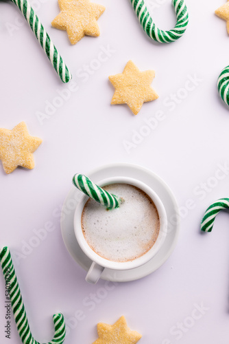 Green christmas canes, christmas cookies and cup of coffee over white background