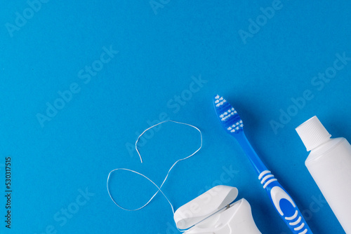 Image of toothbrush, toothpaste and dental string on blue surface