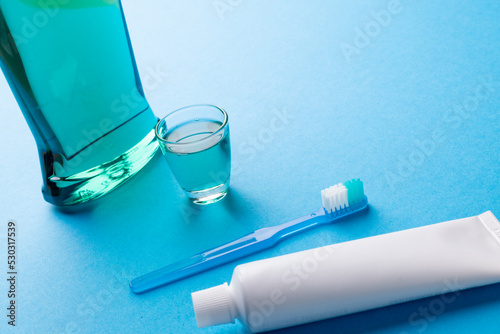 Image of cleaning liquid, toothbrush and toothpaste on blue surface