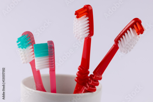 Image of toothbrushes in cup on grey background