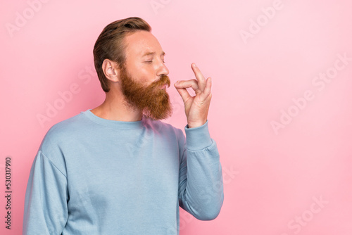 Photo of handsome cheerful man with ginger hairstyle dressed blue long sleeve tasting delicious food isolated on pink color background photo