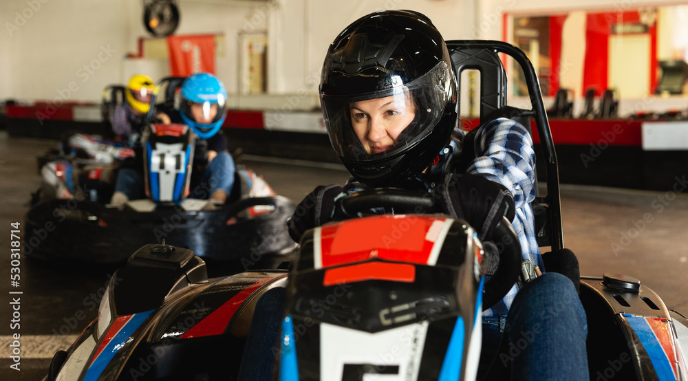 young happy woman driving racing car at kart circuit