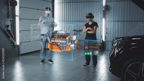 Two service manager engineers use virtual reality technology to diagnose an eco-friendly car engine with an augmented reality interface and 3D engine visualization photo