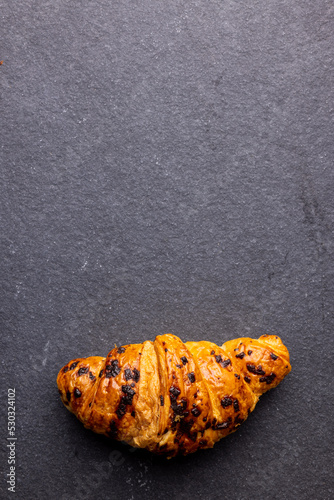 Vertical image of croissants lying on wooden board on dark grey surface