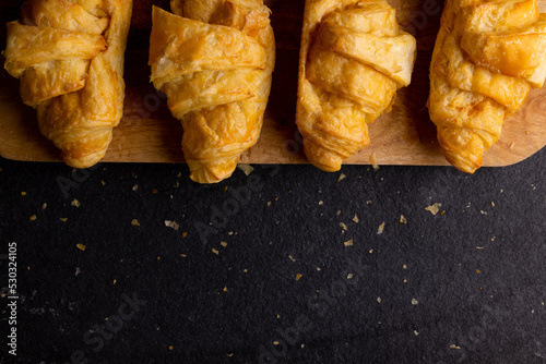 Image of croissants lying on wooden board on dark grey surface
