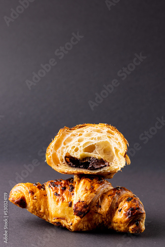 Vertical image of croissants with chocolate on dark grey surface