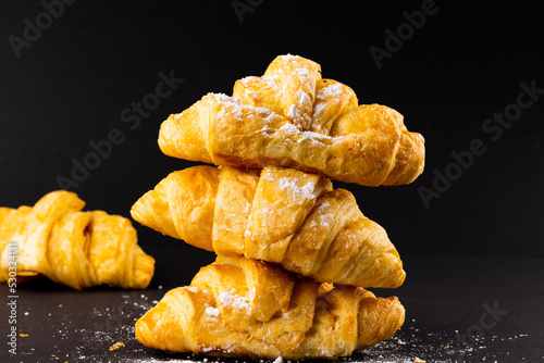 Image of croissants with powder sugar on black background
