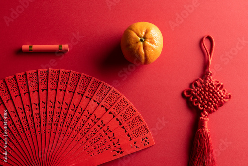 Composition of traditional chinese fan and decorations on red background