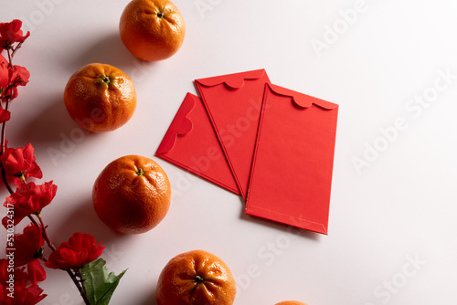 Composition of red flowers, envelopes and oranges on white background