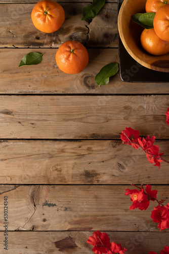 Composition of red flowers and oranges on wooden background