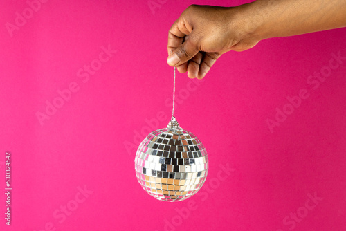 Composition of close up of hand with new years bauble on pink background