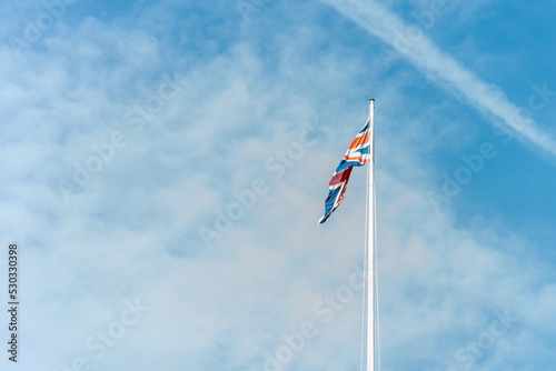 Flag of Great Britain over a light blue sky with some clouds.