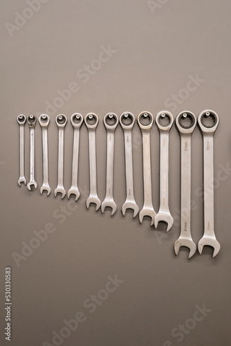 Many wrenches. Grey background. Set of wrenches in different sizes on grey background. Close up.