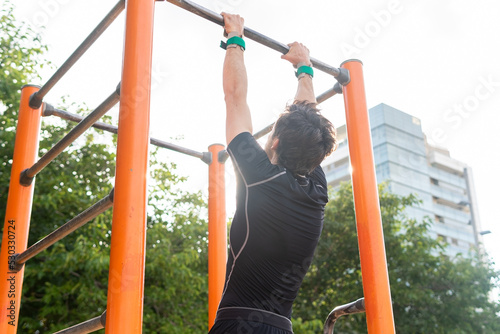 Anonymous hispanic sportsman exercising on bars