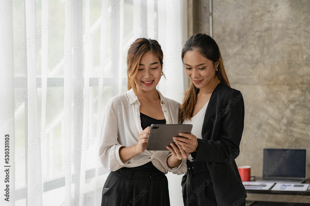 Obraz premium Two beautiful Asian women consulting a collaborative structure using tablets looking at screens for online shopping. internet collaboration concept