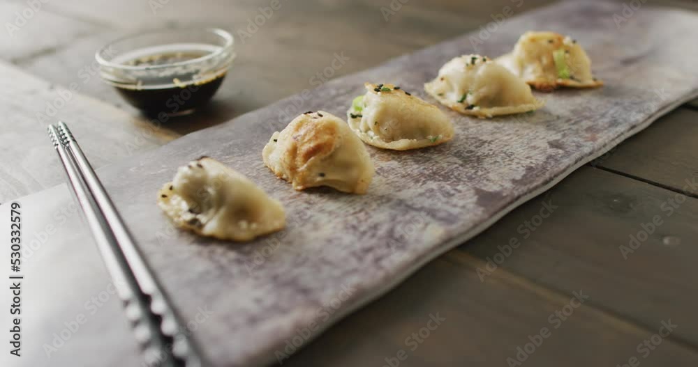 Composition of plate with gyoza dumplings and soy sauce with chopsticks on wooden background Composition of plate with gyoza dumplings and soy sauce with chopsticks on wooden background
