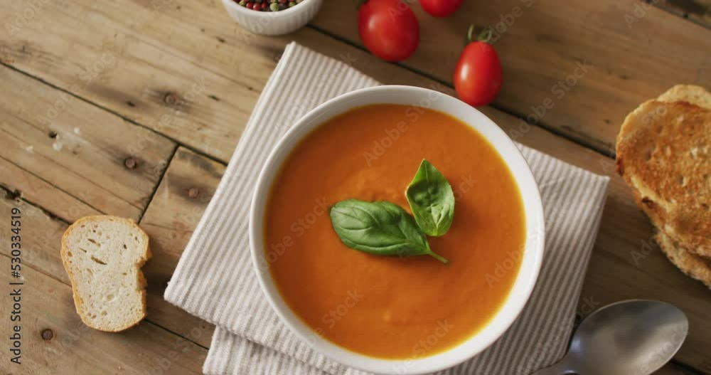 Video of cream tomato soup in bowl on wooden table with bread Video of cream tomato soup in bowl on wooden table with bread
