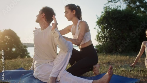 Woman helping man to stretch body during yoga session photo