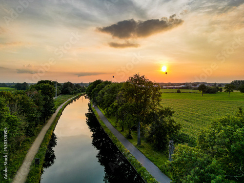 Fotografia Colorful and dramatic sunset over the canal Dessel Schoten aerial photo shot by a drone in Rijkevorsel, kempen, Belgium, showing the waterway in the natural green agricultural landscape