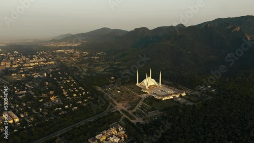 MargallaDrone Orbits around Faisal Mosque durinfg sunrise, the Mosque is one of the biggest in the world and its right between green hills and Islamabad city, good establishing shot. photo