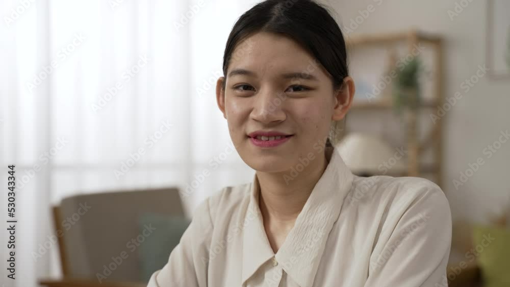 headshot portrait of a beautiful asian businesswoman working from home in white shirt and looking at the camera with a smiling face in a bright living room. headshot portrait of a beautiful asian businesswoman working from home in white shirt and looking at the camera with a smiling face in a bright living room.