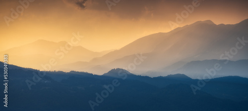Fototapeta Naklejka Na Ścianę i Meble -  Amazing silhouettes of a mountains at colorful sunset in summer in Slovenia. Landscape with mountain ridges in fog, golden sunlight and clouds in the evening. Nature. Hills in sunlight. Scenery