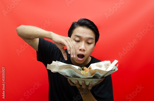 An Indonesian man eats rendang using bare hands without spoon and fork. unique eating customs in indonesia. an indonesian man eats nasi padang.  photo