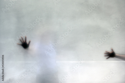 The shadows of two female hands behind frosted glass. Violence against women.