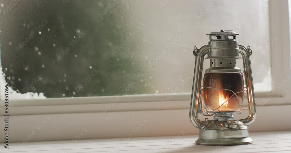Video of glowing vintage oil lamp over frozen and snowy window