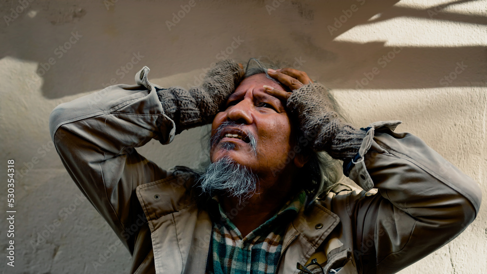 Close Up The face of a dirty-dressed, long-haired, long-haired old man, who is homeless, is showing signs of serious stress because he has no food to eat and no work to sleep on the streets. Close Up The face of a dirty-dressed, long-haired, long-haired old man, who is homeless, is showing signs of serious stress because he has no food to eat and no work to sleep on the streets.