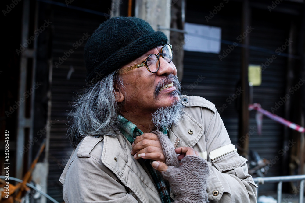 An old homeless Asian man is reaching out to a passerby asking for money for food because he has no job and no home and has to sleep on the streets at night. Homeless not have home.