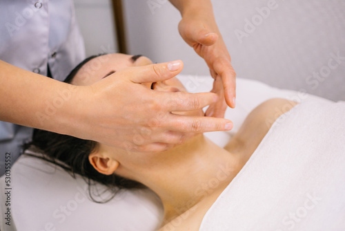Woman receiving facial massage in beauty salon.Beauty and skincare concept with a beautiful woman. Middle aged female relaxed with massage for facial lifting 