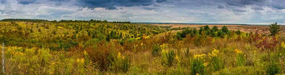 Big panoramic view of autumn landscape under a dramatic cloudy sky. Atmospheric landscape under clouds in rainy weather.