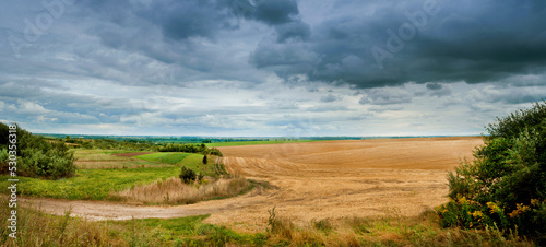 panorama of the field after the harvest and the green field under dark storm ...