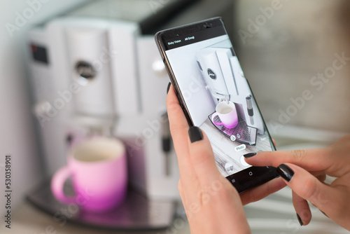 Foto Young woman taking photo of coffee cup and coffeemaker with her smartphone