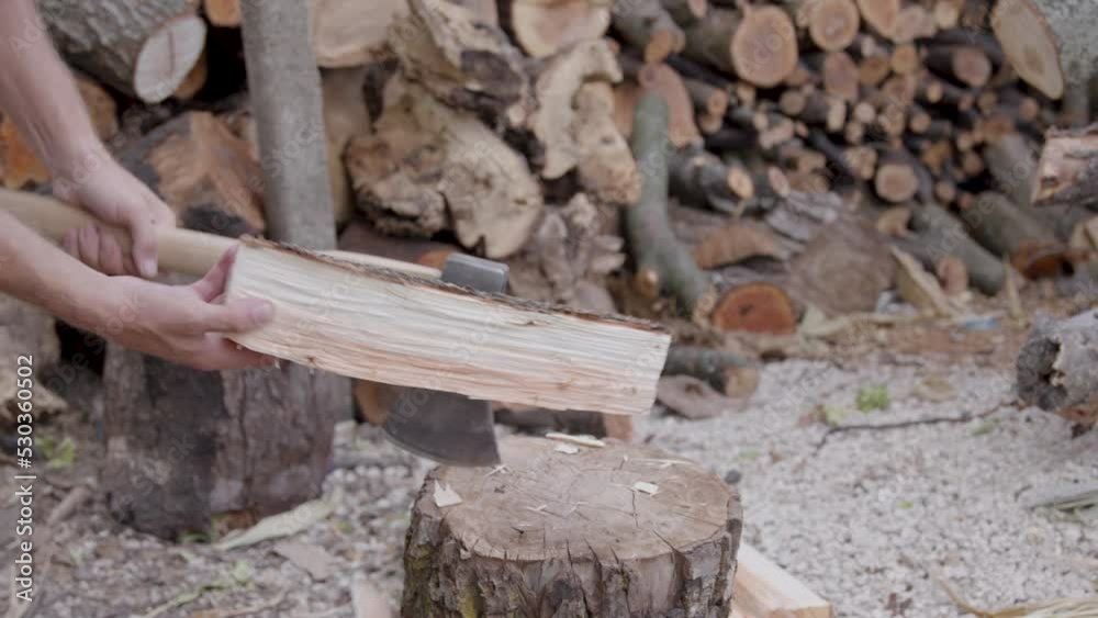 worker cuts wood with ax outside. Close-up shot, behind lots of wood. worker cuts wood with ax outside. Close-up shot, behind lots of wood.
