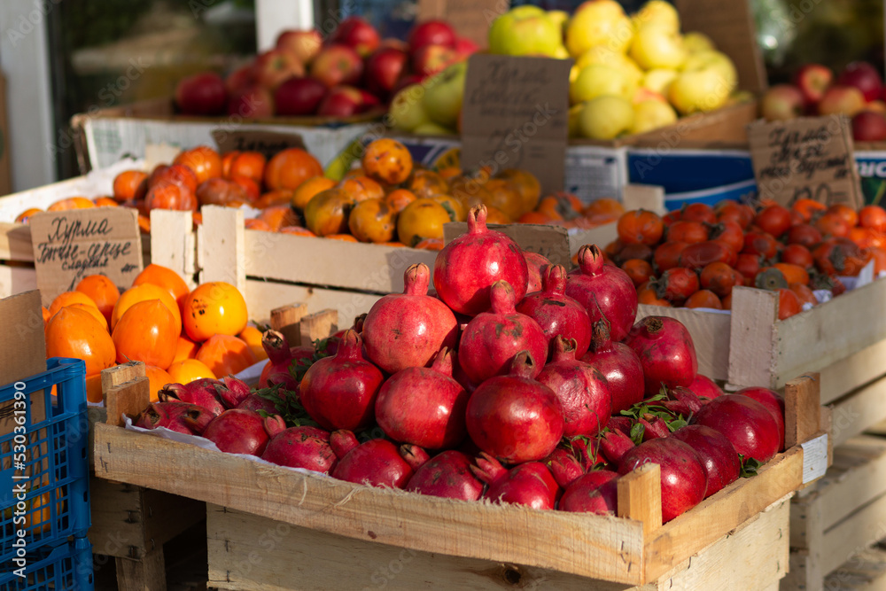 A red ripe pomegranate on the counter of a street vegetable store