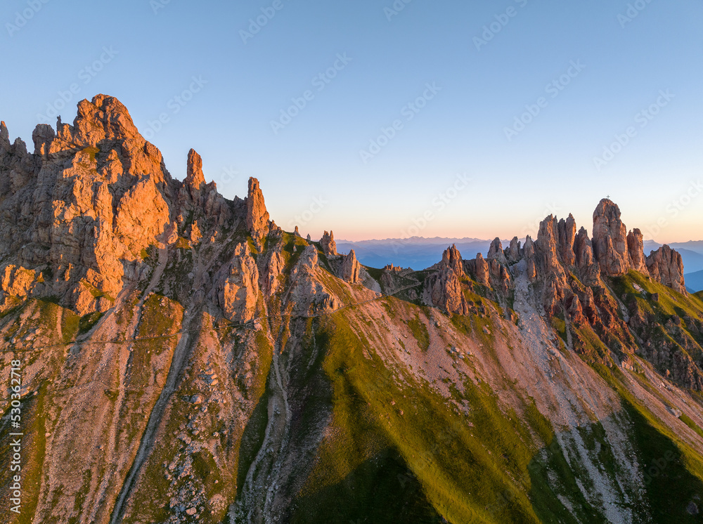 Sunrise in the Dolomites mountains with fog and mist rolling around the peaks. Hiking path leading to the hills.