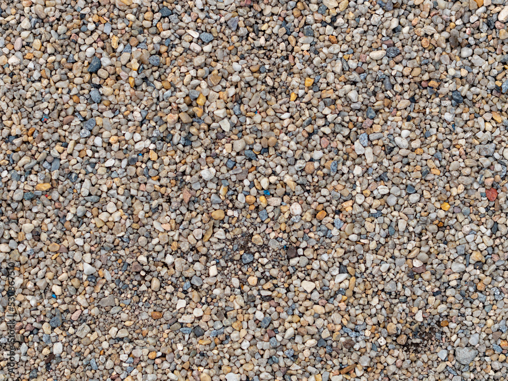 Gravel texture background. A lot of small stones in different sizes and colors. The ground is covered with randomly lying objects. Stone material pattern of a footpath. Gravel texture background. A lot of small stones in different sizes and colors. The ground is covered with randomly lying objects. Stone material pattern of a footpath.