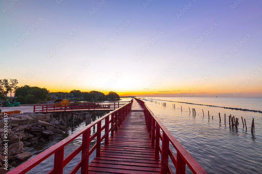 red wooden bridge and sea in the morning,In the morning the red bridge and the sun rise on the horizon. Bridge over the sea in Thailand Thai landscape.